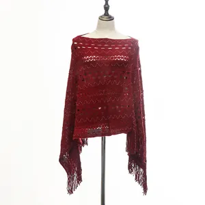 Detail view of a dark red knitted poncho with intricate crochet patterns and tassels.