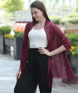 Detailed view of elegant burgundy lace shawl with floral embroidery and tassel fringe.