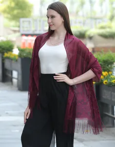 Detail view of a burgundy lace shawl with intricate floral patterns and fringe tassels