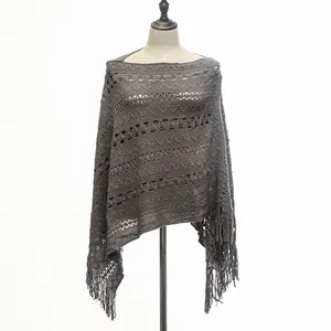 Detailed view of grey knitted poncho with intricate zig-zag patterns and fringe