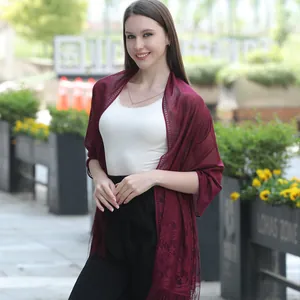 Elegant burgundy lace shawl with floral pattern and fringe details on model