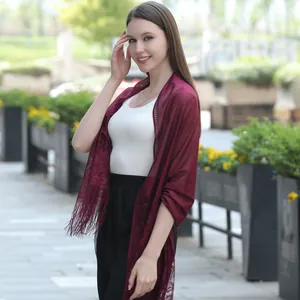 Detailed view of the intricate lace pattern and fringe on this elegant burgundy shawl.