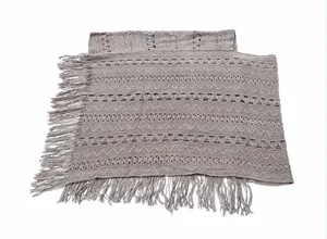 Close-up of grey knitted poncho with intricate geometric patterns and long fringes