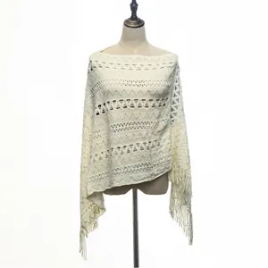 Detailed view of a cream knitted pullover poncho with geometric patterns and fringe.