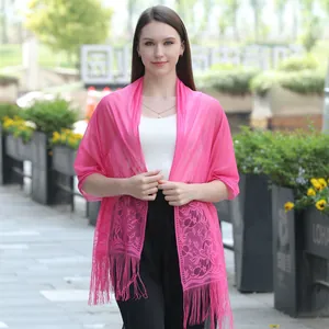 Detailed view of fuchsia lace shawl with floral patterns and tassels on a model