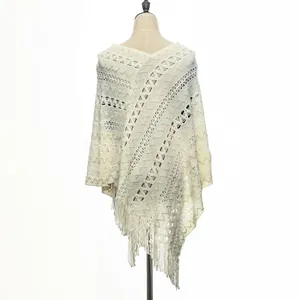 Detailed view of cream knit poncho featuring geometric openwork and long fringe hem
