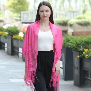 Close-up detail of a vibrant pink lace shawl with intricate floral patterns and fringe.