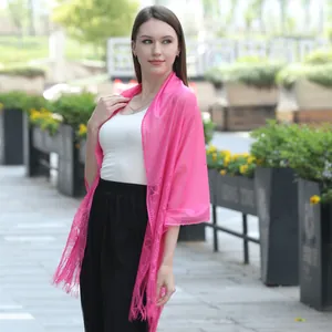 Detail shot of vibrant pink lace shawl with delicate floral embroidery and fringe trim