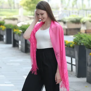 Detail view of an elegant pink lace shawl featuring intricate floral patterns and fringe