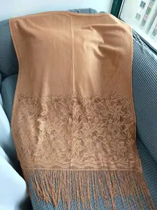 Close-up view of tan lace shawl with floral embroidery and elegant long fringe details