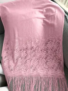Close-up detail of the delicate floral lace pattern and pink fringe on the shawl.