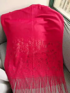 Close-up of elegant fuchsia lace shawl with intricate flower embroidery and long fringes