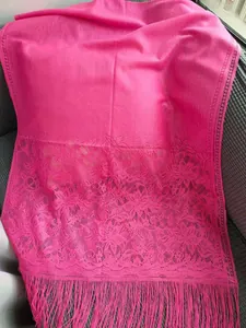 Close-up detail of fuchsia lace shawl with elegant floral patterns and fringe tassels.