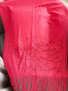 Close-up of elegant pink lace shawl featuring delicate floral embroidery and long fringe details.