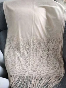 Elegant beige lace shawl scarf with floral patterns and fine fringe details close-up