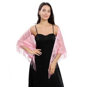 Vue détaillée d'un élégant châle en dentelle rose avec pompons porté sur une robe de soirée