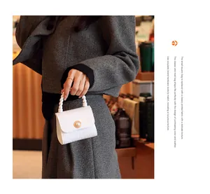 Macro view of white mini jelly handbag featuring pearl clasp and elegant twisted handle
