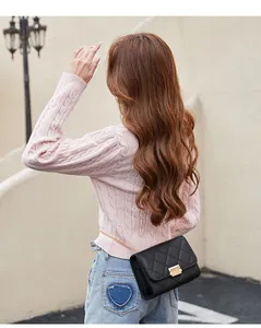 Rear view of a model wearing a stylish black quilted crossbody bag with gold chain