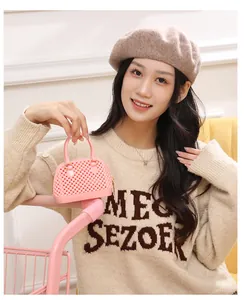Close-up of a pink jelly mini shell handbag held by a model in a beige sweater