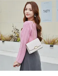 Lifestyle detail of a white quilted crossbody bag with gold chain strap on a model.