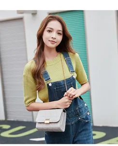 Fashionable grey crossbody bag with triangle embroidery and gold chain strap on a model