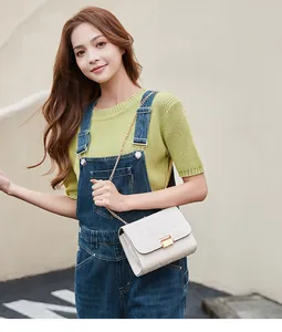 Model wearing a stylish white chain crossbody bag with triangular embroidery and gold lock