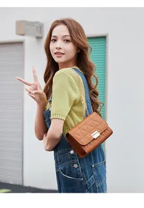 Asian model wearing a brown quilted chain cross-body bag with triangle embroidery