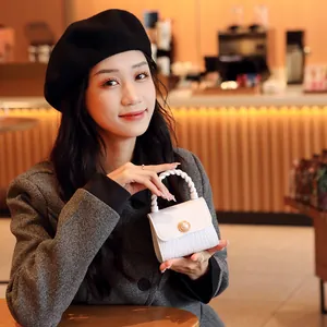 Elegant white mini pearl handbag with crocodile texture held by model