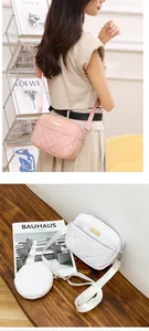 Detailed view of fashionable quilted crossbody bag and round coin purse on a wooden surface