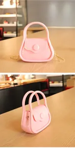 Gros plan d'un sac à main en gelée rose bonbon avec finition brillante et chaîne dorée