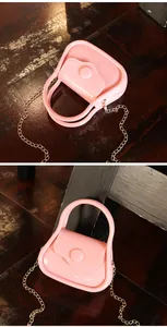 Détail d'un sac en gelée rose bonbon brillant avec poignée et bandoulière chaîne dorée.