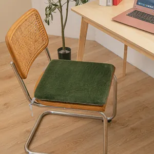 Detail view showing the soft texture of a plush green heating chair cushion on a wooden chair