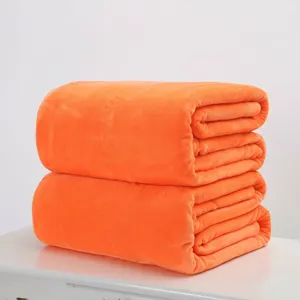 Hochwertige weiche orangefarbene Flanell-Fleecedecke ordentlich gefaltet auf weiß