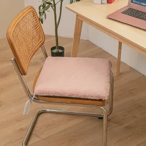 Comfortable soft plush pink seat cushion with ties on a retro wooden rattan chair