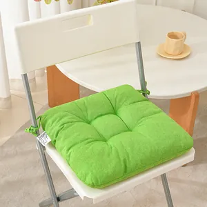 Detailed view of a thickened green cloth chair cushion with secure straps on a white folding chair