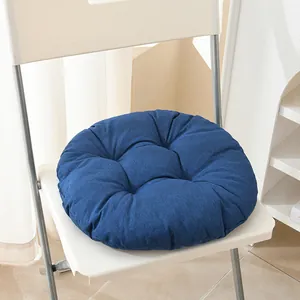 Nahaufnahme eines dicken blauen Leinen-Sitzkissens mit getuftetem Design auf weißem Stuhl.