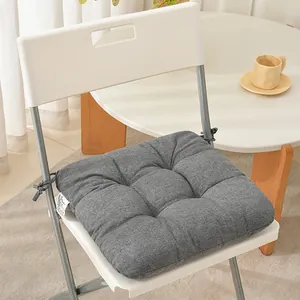 Close-up of thick grey tufted seat cushion with ties on a white chair