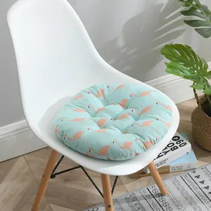 Détail d'un coussin de chaise rond en coton et lin à motif flamant rose sur chaise blanche