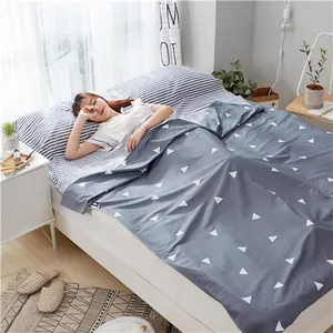 Detail view of a portable cotton travel sleeping bag with white triangle patterns in use.