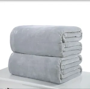 Macro detail of two stacked soft grey flannel fleece blankets on white surface