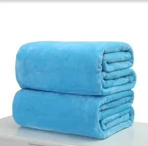 Close-up of two stacked folded light blue soft flannel fleece blankets on a white surface