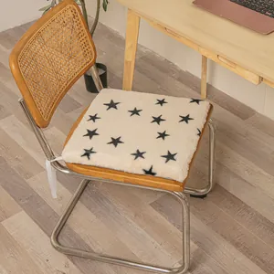Square plush chair cushion with black star pattern shown on a wooden chair in office