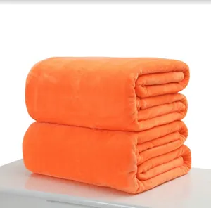 Macro detail of soft orange flannel blanket showing plush texture and neat folding