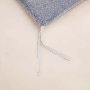 Detail view of plush heated seat cushion showing grey fabric texture and white tie straps