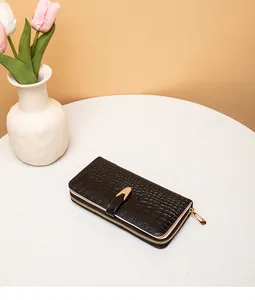 Elegante cartera larga de mujer en color negro con grabado de cocodrilo sobre mesa