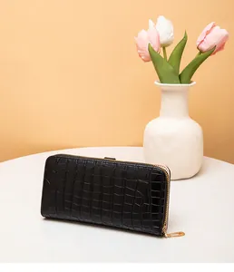 Vista detallada de una cartera larga para mujer en color negro con textura de cocodrilo.