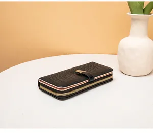 Primer plano de una cartera larga negra con textura de cocodrilo y cierre de serpiente.