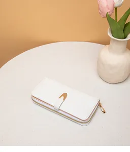 Vista de detalle de una cartera larga blanca con patrón de piedra para mujer en una mesa