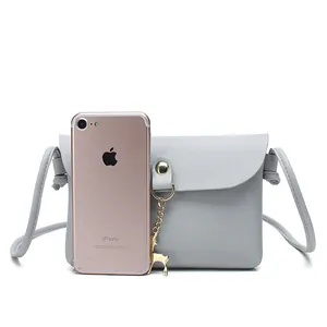 Mini grey crossbody phone bag with gold deer charm, shown next to a phone for scale.