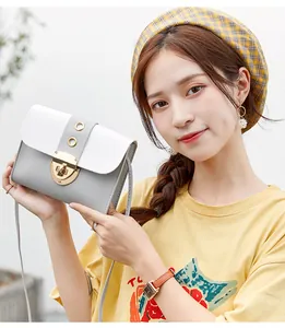 Asian model holding a small grey and white color-block crossbody bag with a gold metal lock